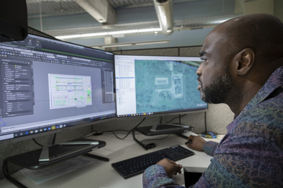 Engineer sitting in front of two computer screens displaying GIS